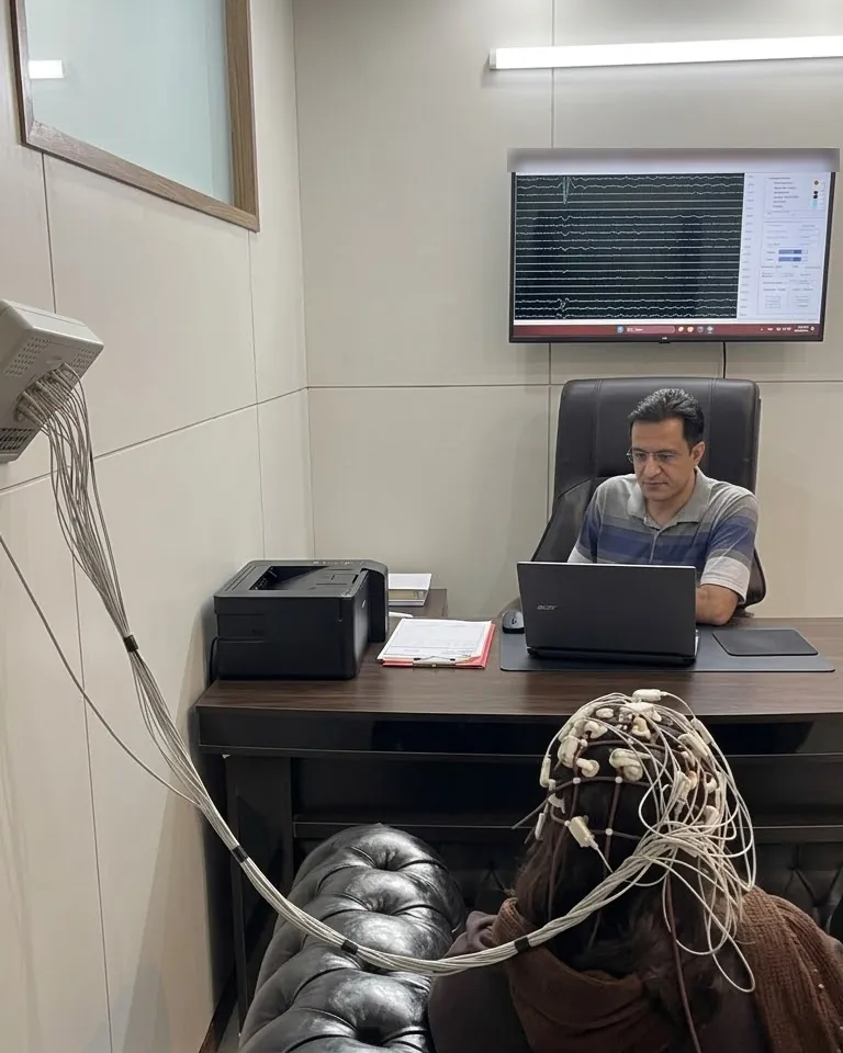 دکتر داود صمدی در کلینیک تخصصی علوم اعصاب و مغز در مشهد هنگام ثبت نقشهٔ مغزی (QEEG) یک مراجع؛ کلاه الکترود روی سر مراجع و امواج مغزی روی نمایشگر دیده می‌شود.